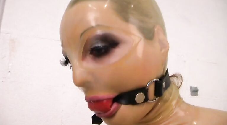 Cute girl encased in latex, with a ballgag, locked on a sybian and to cum